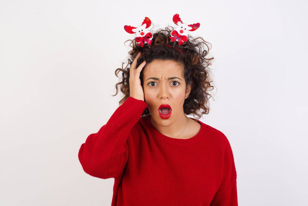 woman with curly hair wearing deer horns headband, shocked expression, expresses great amazement - Photo, Image