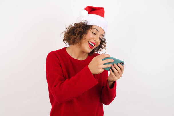happy woman in holding smartphone and wearing santa hat  - Фото, изображение