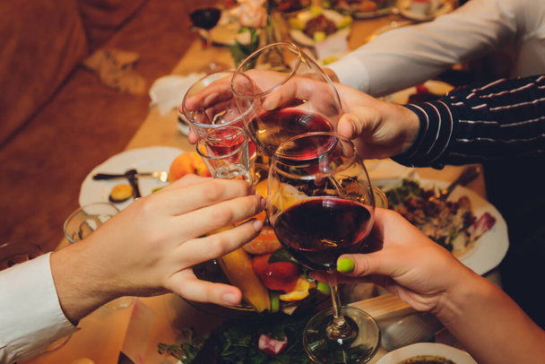 Close up shot of group of people clinking glasses with wine or champagne in front of bokeh background. older people hands. - 写真・画像