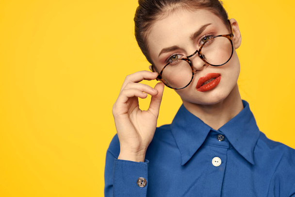 A woman in a blue shirt and glasses with bright makeup on her face is gesturing with her hands Copy Space - 写真・画像