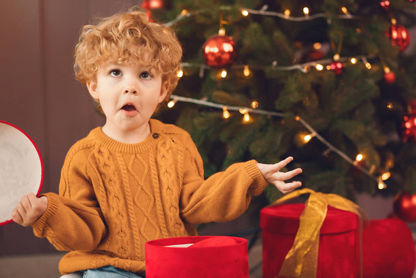Little boy near christmas tree in a brown sweater - Φωτογραφία, εικόνα