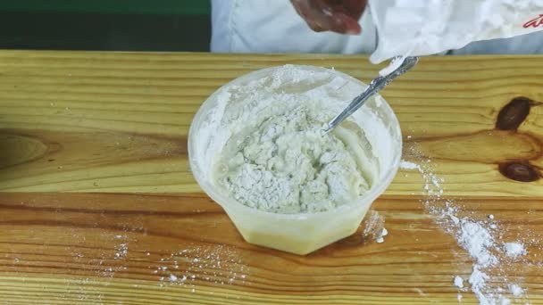 vue du dessus sur les mains de l'homme verser de la farine blanche dans une pâte molle dans un bol en plastique profond - Séquence, vidéo