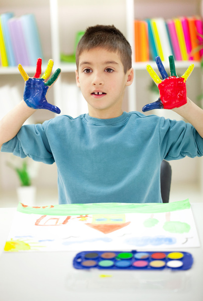 jongen met handen geschilderd in kleurrijke verf klaar voor hand afdrukken - Foto, afbeelding
