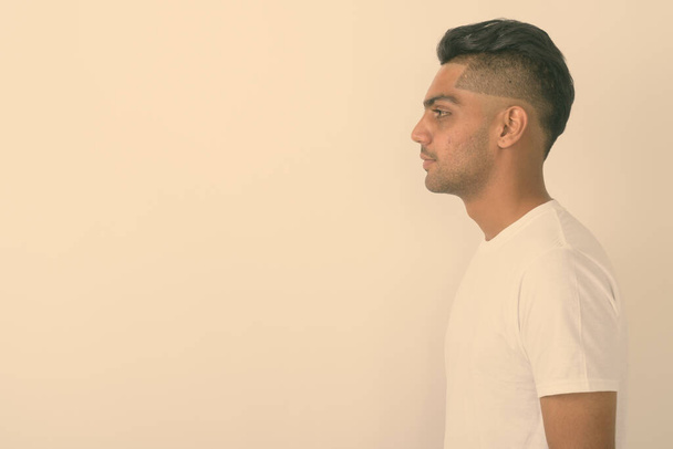 Profile view of young Indian man against white background - Photo, Image