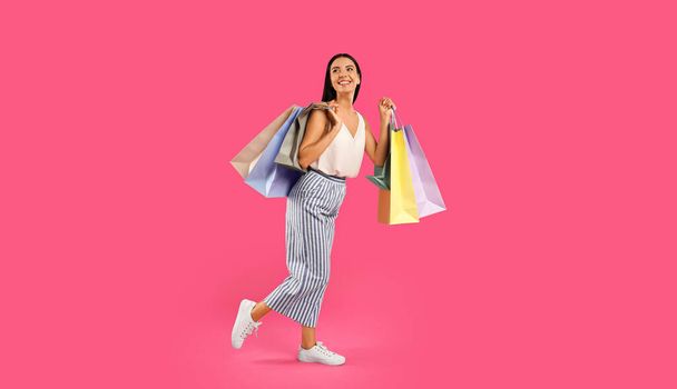 Beautiful young woman with paper shopping bags on pink background - Fotografie, Obrázek