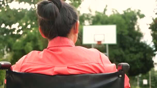 Jonge vrouw die op een rolstoel zit en gebaren maakt gooit een bal in het stadion. De hoop van het gehandicaptenconcept. - Video