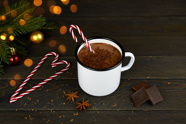 Homemade hot chocolate with cinnamon in a white enamel mug on a dark wooden background. Christmas  and new year composition. - Foto, imagen