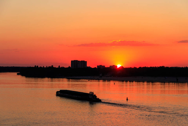 Remolcador empujando una larga barcaza pesada en el río Dnieper al atardecer - Foto, Imagen