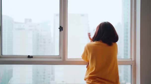 Asiatin schaut nach draußen, nachdem sie eingesperrt wurde. Gefühl von Einsamkeit und Heimweh, Konzept zu Hause bleiben - Filmmaterial, Video