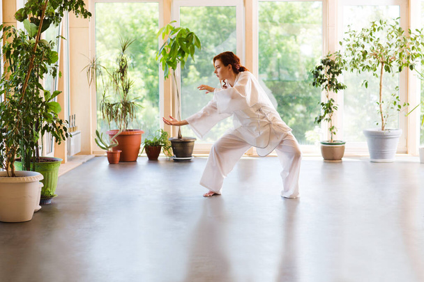 Young Woman praticing tai chi chuan in the gym. Chinese management skill Qi's energy. - Foto, afbeelding