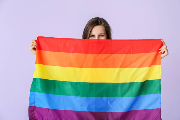 Young woman with LGBT flag on color background - Foto, afbeelding