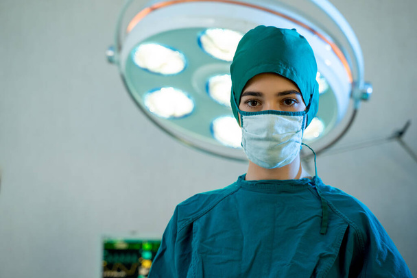 Portret chirurga stojącego na sali operacyjnej, gotowy do pracy na pacjencie, pracownik medyczny w mundurze chirurgicznym na sali operacyjnej w szpitalu. - Zdjęcie, obraz