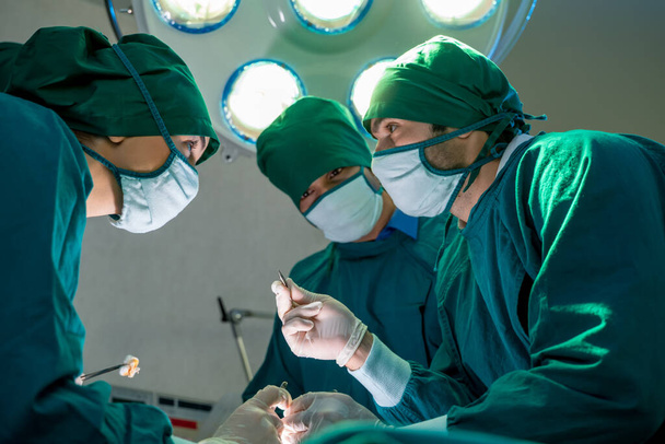 Команда врачей делает операцию, чтобы спасти жизни в операционной в больнице, хирургии, медицины и людей концепции.  - Фото, изображение