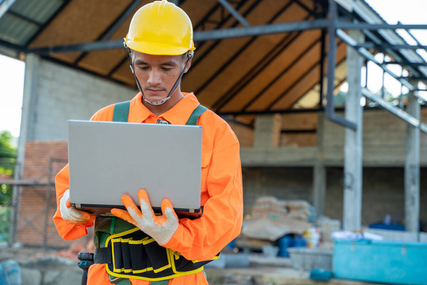 Elektrotechniker tragen Sicherheitsgurt mit Laptop auf Baustelle. - Foto, Bild