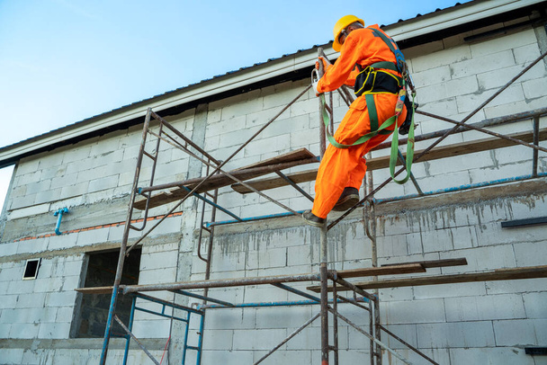 Rakennustyöntekijä käyttää turvavyötä työskennellessään korkealla paikalla rakennustyömaalla. - Valokuva, kuva