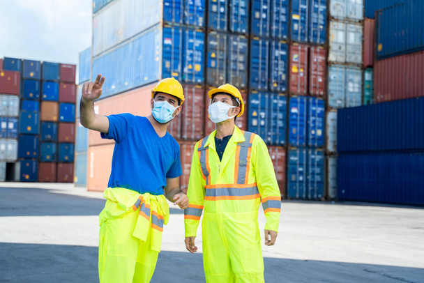 Technicus of ingenieur draagt beschermend masker te beschermen tegen Covid-19 discussie en praten voor inspectie bij containerlading, Business Logistics import export verzendconcept. - Foto, afbeelding