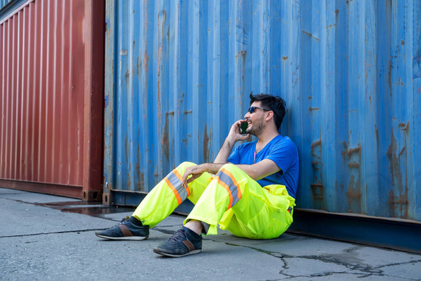 Containerarbeiter sitzt am Containerfrachtraum und ist traurig und enttäuscht. - Foto, Bild
