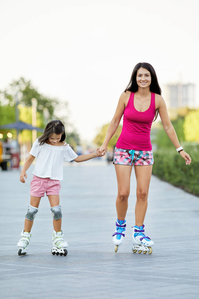 Young mother and her little daughter rollerskating - Photo, Image