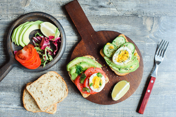 healthy vegetarian breakfast, avocado toast with cucumber, eggs, tomato and greean salad on wholegrain bread - Photo, image