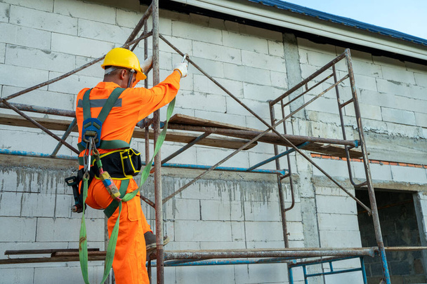 Lavoratori edili che indossano cinture di sicurezza durante il lavoro in alto, concetto di edificio residenziale in costruzione. - Foto, immagini