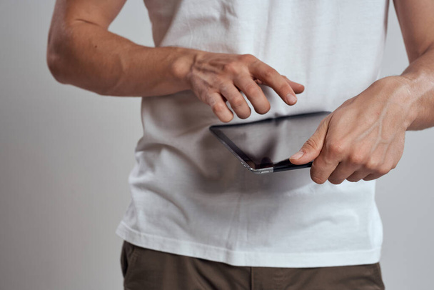 Tabletka z ekranem dotykowym na jasnym tle męskie ręce biały t-shirt przycięty widok - Zdjęcie, obraz