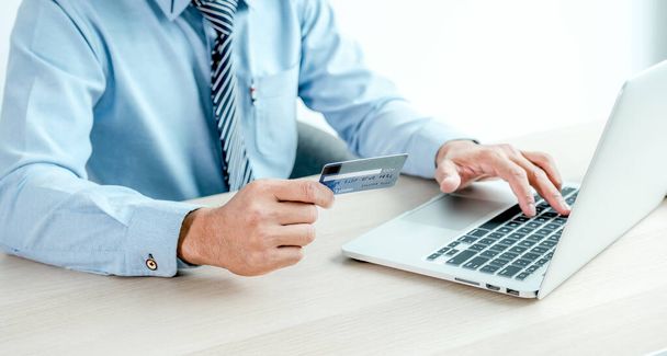 Zakenman hand houden credit card om online winkelen vanuit huis met laptop, betaling e-commerce, internetbankieren, geld uitgeven voor de volgende vakantie. - Foto, afbeelding