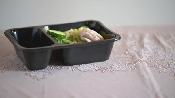 A woman puts a plastic container with a healthy salad on the table and eats. Female hands with fork close-up. Homemade ready meals delivered from a restaurant, ordered by phone. Diet, healthy snack - Footage, Video