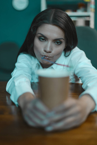 Tired young business woman drinks coffee. Bored woman at office workplace. Crisis concept. Tinted image - Фото, зображення