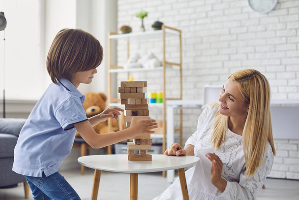 Happy mother and son play board games in the living room. Family has fun playing genga at home - Φωτογραφία, εικόνα