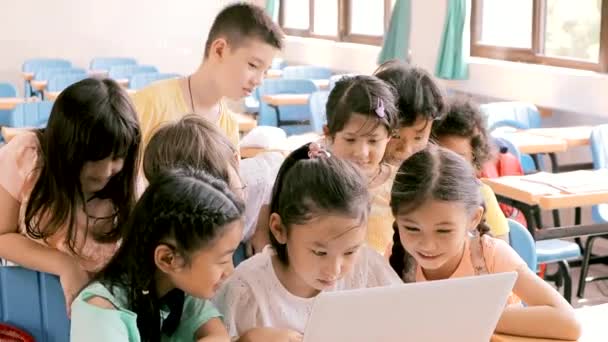 Niños felices viendo el portátil y discutiendo en el aula - Imágenes, Vídeo