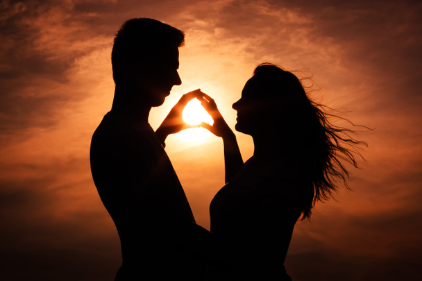 a szeretet sziluettje során naplemente - megérintette a kezét pár - Fotó, kép
