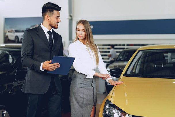 Man car dealer showing a woman buyer a new car - Φωτογραφία, εικόνα