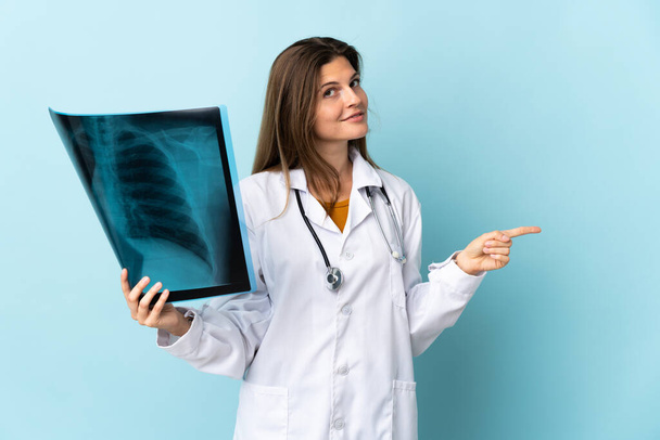 Молодая женщина-врач проводит радиографию на изолированном фоне, указывая пальцем в сторону - Фото, изображение