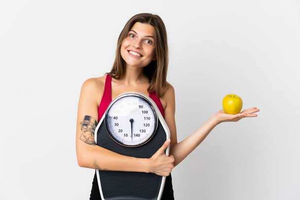 Young slovak woman isolated on white background with weighing machine and with an apple - Photo, Image
