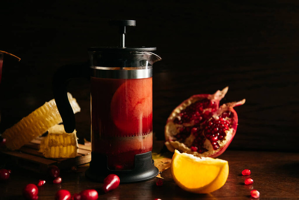 Pomegranate tea in french press with honey and orange on the table in restaurant - Foto, Imagem
