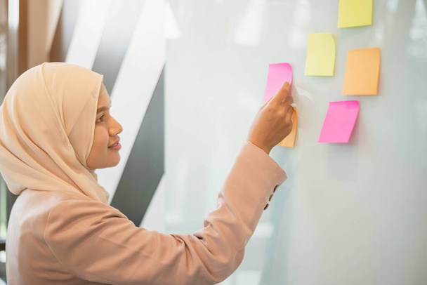 Donna musulmana mettendo posta adesivi nota. concetto di brainstorming e creatività. - Foto, immagini