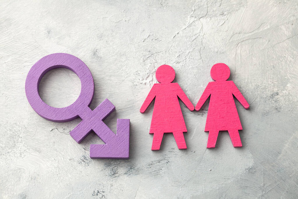 Cinsiyet değiştirme sembolü arka planında el ele tutuşan iki lezbiyen. - Fotoğraf, Görsel
