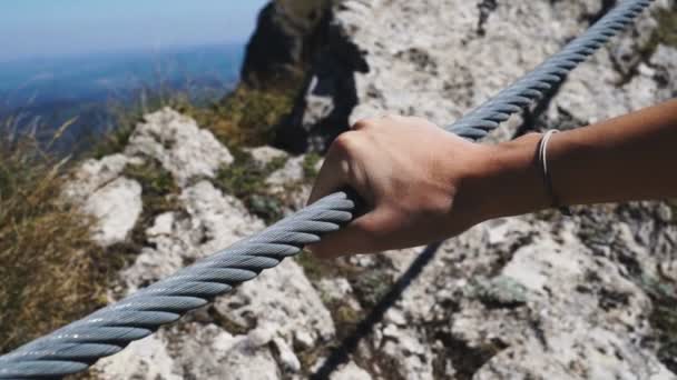 Samičí ruka drží pevně ocelové lano mostu vysoko v horách - Záběry, video