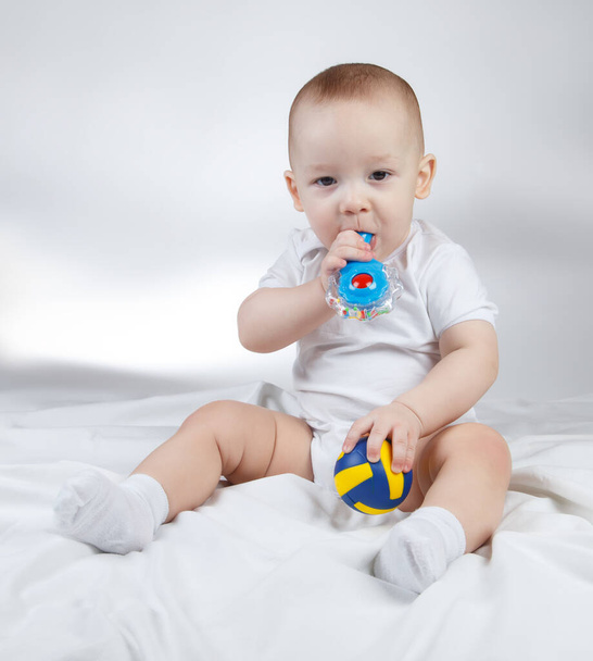 Foto eines zehn Monate alten Babys mit Rassel und Ball - Foto, Bild