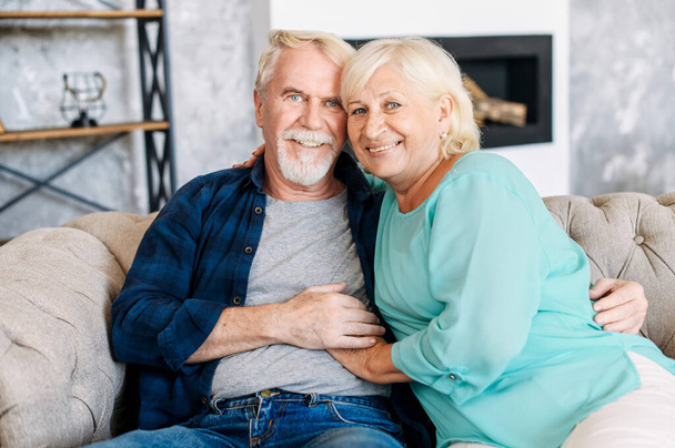 Senior couple sits on the sofa at home - Foto, afbeelding