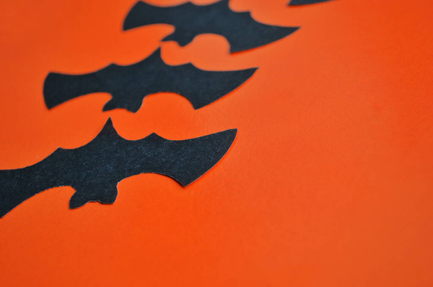 Schwarze Papierfledermäuse liegen auf orangefarbenem Hintergrund - Foto, Bild