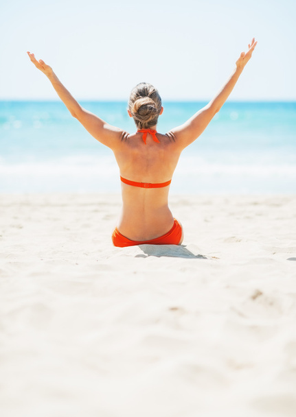 Jovem mulher sentada na praia e se alegrando
 - Foto, Imagem