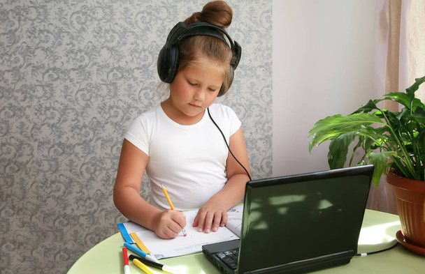 Soustředěná dětská sebeizolace nošení sluchátek pomocí notebooku v kavárně, psaní poznámek, studentská výuka jazyka, sledování online webináře, Home schooling, e-learning education concept - Fotografie, Obrázek