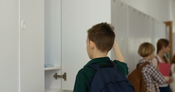 Ragazzo adolescente caucasico che tira fuori libri di testo dal suo armadietto e poi se ne va per il corridoio della scuola alla lezione. - Filmati, video