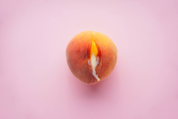 Saftiger Pfirsich und Kondensmilch auf rosa Hintergrund, Draufsicht. Sexualkonzept. - Foto, Bild