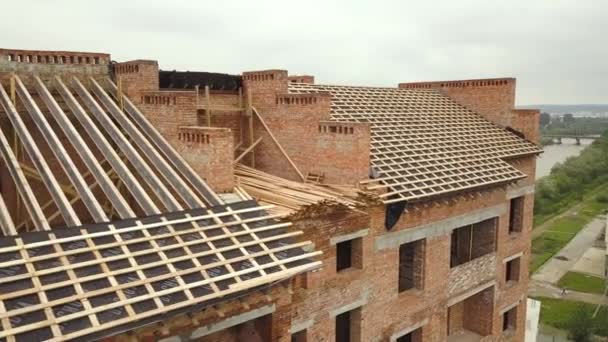 Aerial view of unfinished brick apartment building with wooden roof structure under construction. - Footage, Video