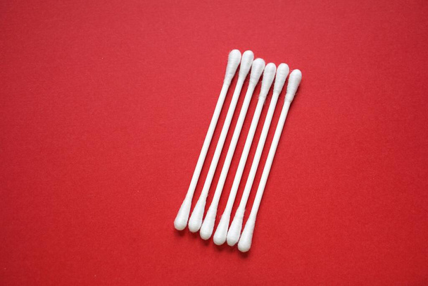 white cotton swabs on the red background, hygiene products                     - Fotografie, Obrázek
