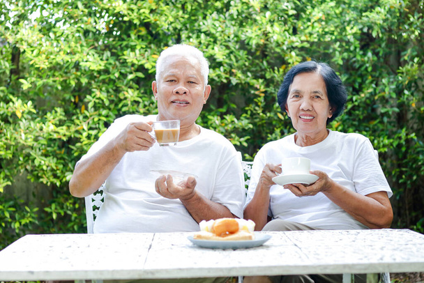 Asijské starší pár sedí v dopoledních hodinách pít kávu a chatování na předním dvoře. Senior zdravotní péče, důchodové bydlení. - Fotografie, Obrázek