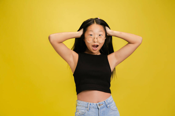 Portrait of young asian girl isolated on yellow studio background - Fotografie, Obrázek