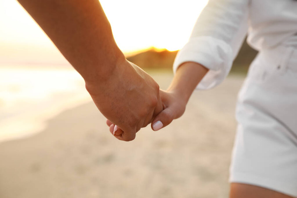 Lovely couple holding hands on beach, closeup - Foto, Imagen